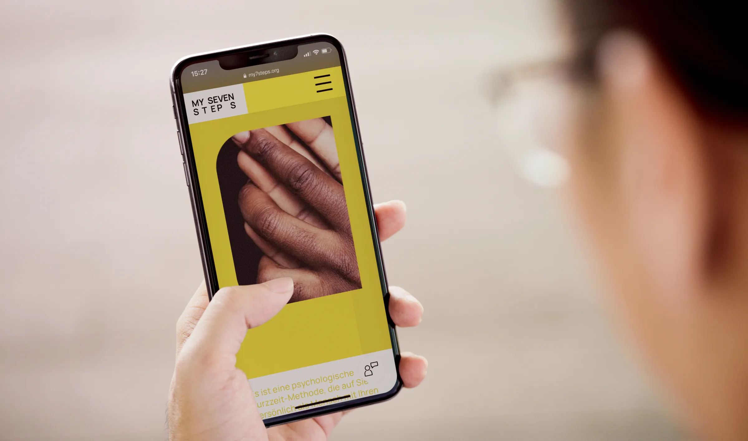 Hand hält ein Smartphone mit der gelben My-Seven-Steps-Website